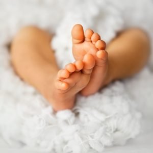 Newborn baby feet on a white soft background, vertical composition